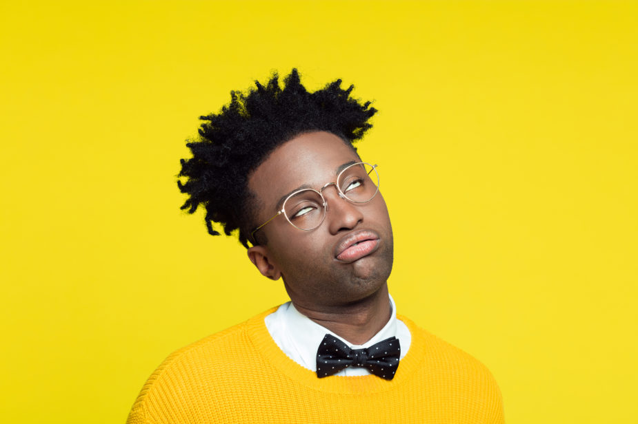 Portrait of bored geeky young man in retro style against yellow background